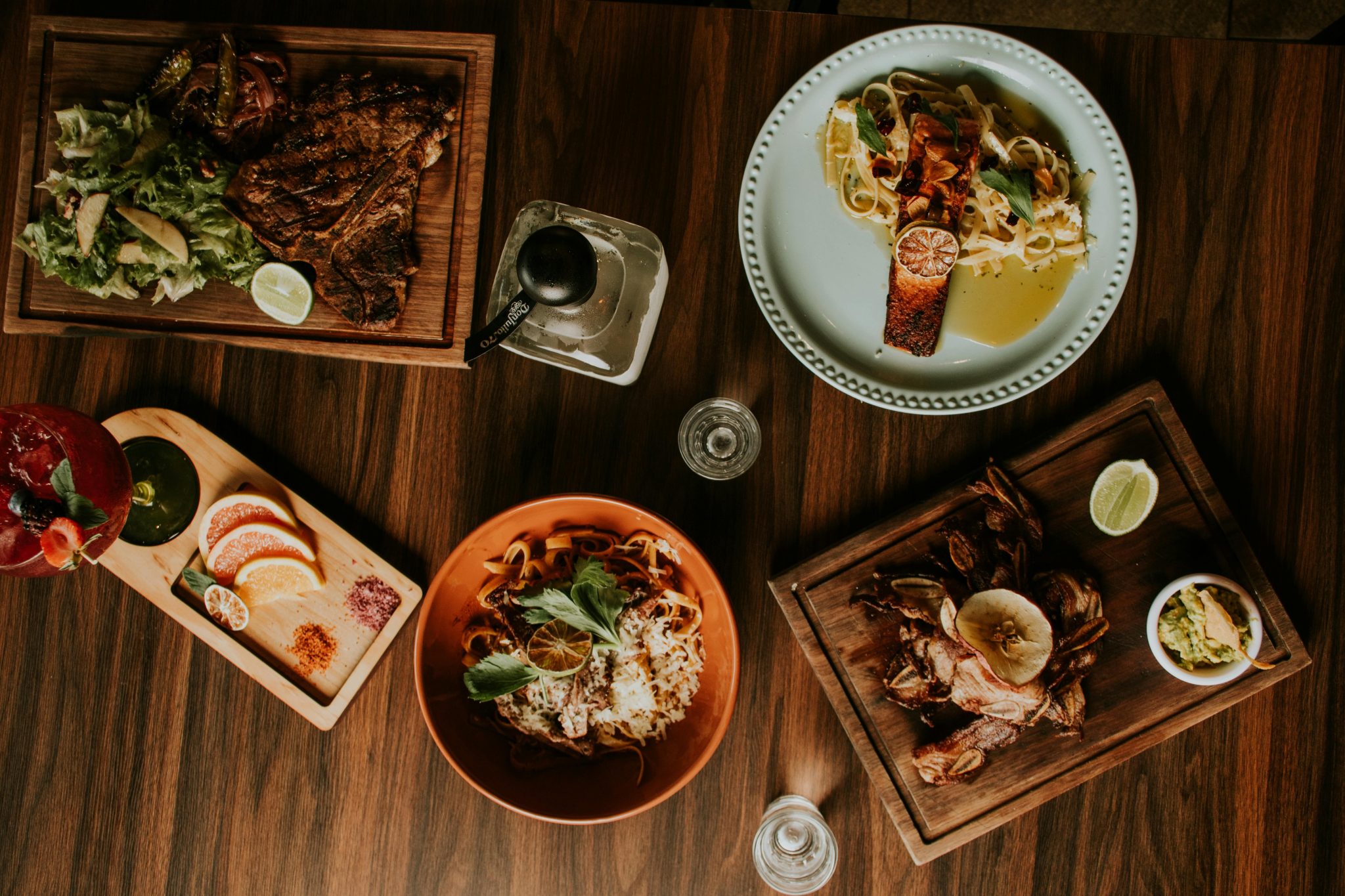 Elegant display of diverse gourmet dishes served on a wooden table from above.