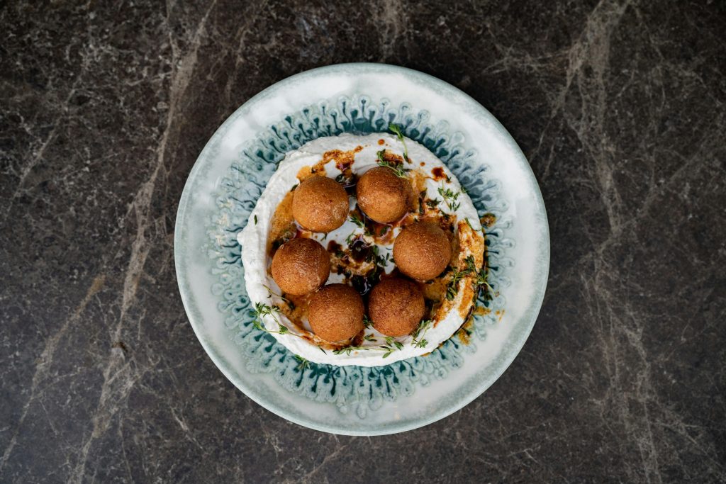 A top view of crispy falafel balls served with a creamy dip on a decorative plate, perfect for food enthusiasts.