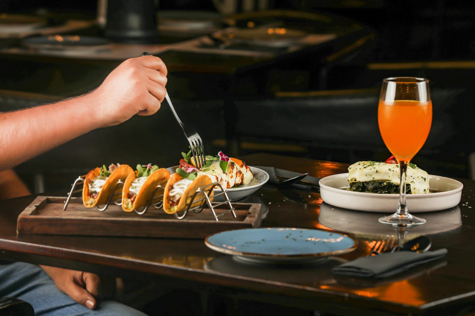 A flavorful dining setup featuring tacos, a refreshing beverage, and a gourmet plated dish indoors.